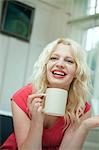 Young woman in conversation, holding a hot drink