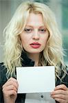 Serious young woman holding a blank card