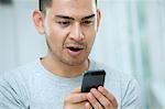 Mid adult man looking surprised at smartphone