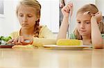 Girls poking vegetables on plate