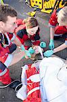 Three paramedics with patient on stretcher wearing oxygen mask