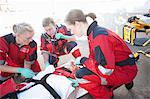 Three paramedics with patient on stretcher wearing oxygen mask