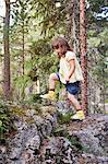 Girl climbing over rocks in forest