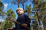 Boy standing in forest holding stick