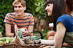 Friends sitting in garden with basket of fresh vegetables