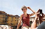 Man photographing woman on Ponte Vecchio, Florence, Tuscany, Italy