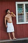 Young man drinking a beer outside sauna
