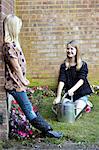 Two girls in garden watering flower bed