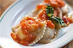 Still life with ravioli, tomato sauce and basil garnish