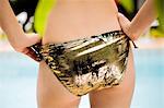 Close up portrait of female buttocks wearing gold bikini bottoms