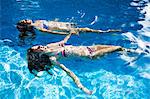 Two teenage girls floating in swimming pool
