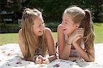 Two teenage girls lying on picnic blanket