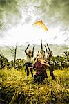 Five young women flying kite in scrubland