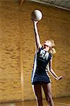 Portrait of netball player reaching for ball