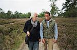 Father and adult son walking on dirt track