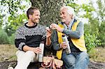 Father and adult son drinking coffee from flask