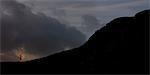 Young man running up silhouetted mountain