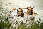 Two young women making faces with grass