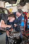 Mechanics working on car engine in garange