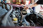 Mechanic pouring liquid into car