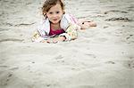 Portrait of female toddler lying in sand