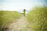 Female toddler carrying long stick