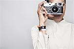 Studio portrait of mature woman holding up camera