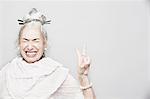 Studio portrait of sophisticated senior woman making victory sign