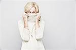 Studio portrait of senior woman hiding behind roll neck