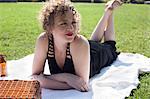 Young woman lying on picnic blanket in park