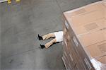 Man lying on floor with cardboard boxes in warehouse