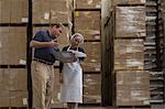 Factory worker and manager looking at clipboard in warehouse