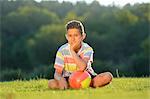 Teeange boy sitting with football on meadow, Upper Palatinate, Germany, Europe