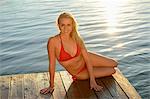 Young blond woman in bikini on a jetty at a lake, Styria, Austria