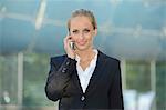 Young blond business woman with cell phone outdoors, portrait