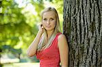 Young blond woman at a tree trunk in a park