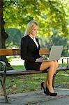 Young blond business woman with laptop in a park