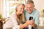 Senior couple sharing mp3 player in domestic kitchen