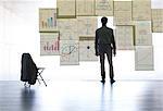 Businessman looking at graphs and charts on glass wall in office