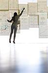 Businesswoman writing on paper on glass wall