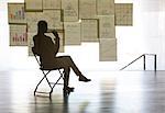 Businesswoman studying charts and graphs on wall in office