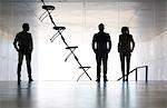 Business people standing next to office chair installation art