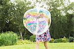 Father and daughter playing with large bubbles in backyard