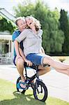 Couple riding small bicycle in grass