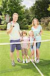 Family smiling together on grass tennis court