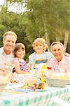 Multi-generation family eating lunch at table in backyard