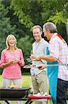 Family standing at barbecue in backyard