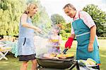 Multi-generation family standing at barbecue in backyard