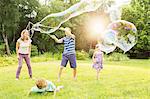 Family playing with large bubbles in backyard