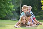 Children laying on mother in grass